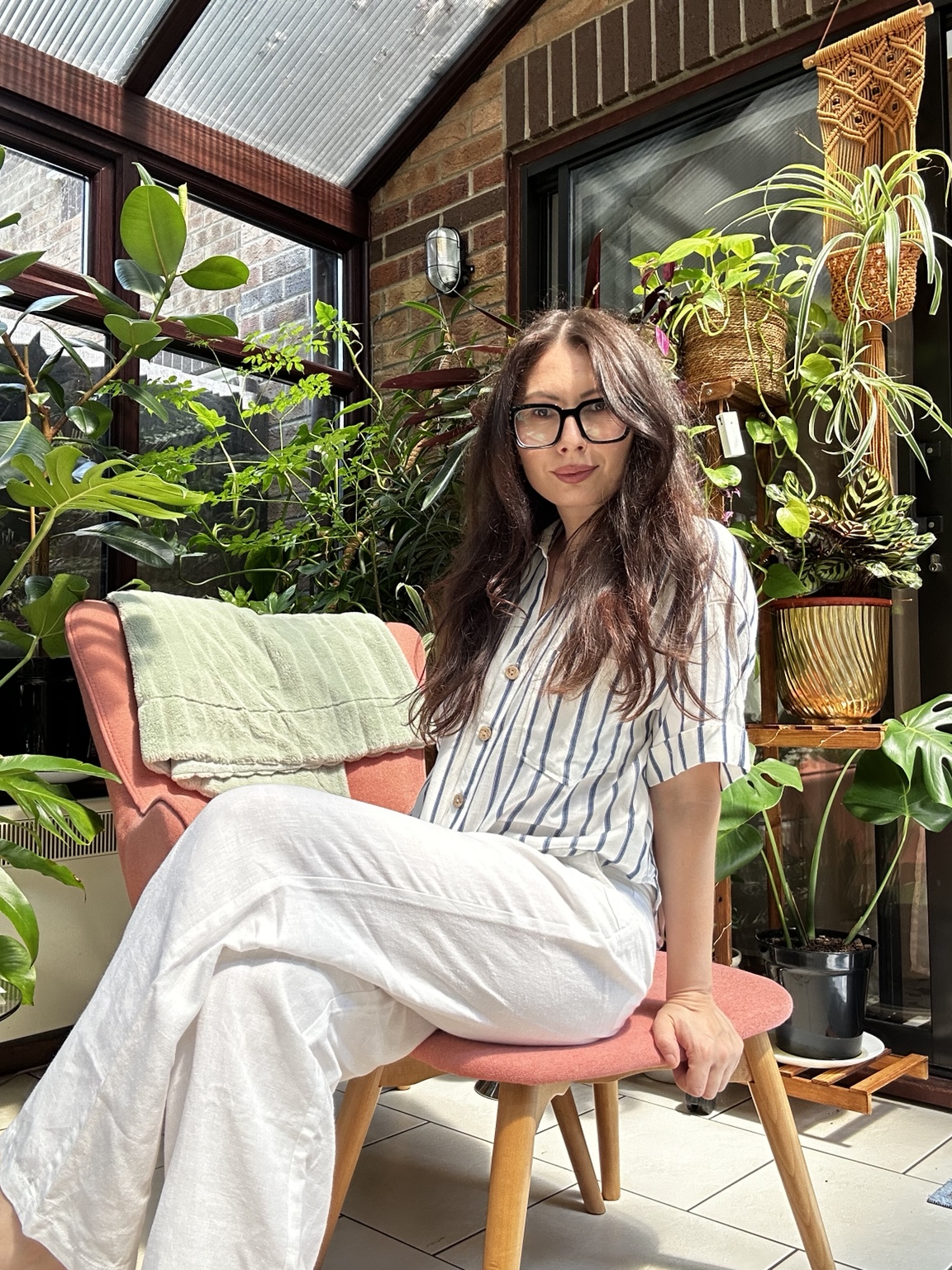 Adina, founder of First Guest, seated in a plant-filled conservatory
